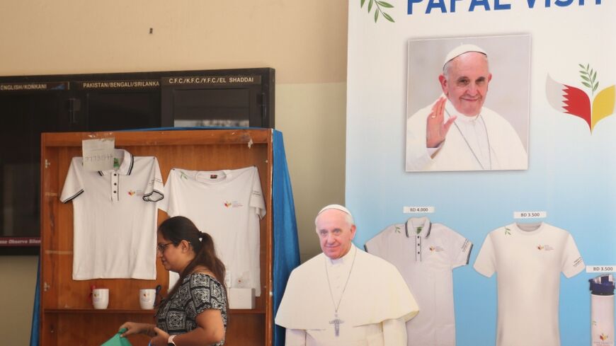A woman walks past a cutout image of Pope Francis in Bahrain's capital Manama