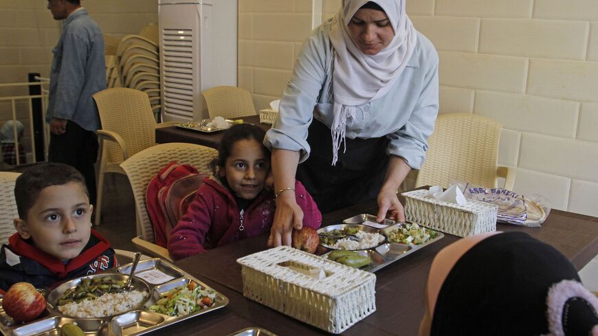 A volunteer serves food to needy children at a kitchen set up by charity groups in Lebanon's southern city of Sidon on Dec. 7, 2019.
