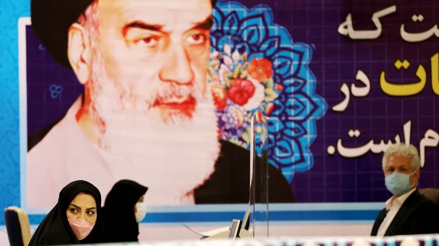 Staff members sit under a portrait of the Islamic Republic's late revolutionary leader Ayatollah Ruhollah Khomeini.