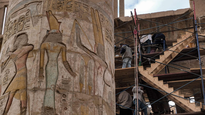 Conservationists restore some of the hieroglyphic murals along the roof of the Great Hypostyle Hall next to a column bearing a representation of the Egyptian god Amun-Min in the Temple of Karnak, Luxor, Egypt, Jan. 17, 2022.