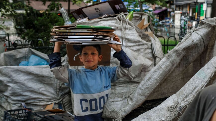 Seyit, an 8-year-old Kurdish garbage collector, carries flattened cardboard boxes in Istanbul on Sept. 12, 2022.
