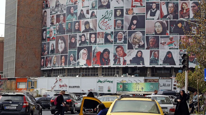 Iranians drive past a huge billboard showing a montage of pictures titled "The women of my land, Iran."