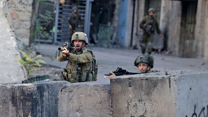 Israeli security forces take cover from Palestinian stone-throwers amid clashes in the West Bank city of Hebron on Nov. 4, 2022. 