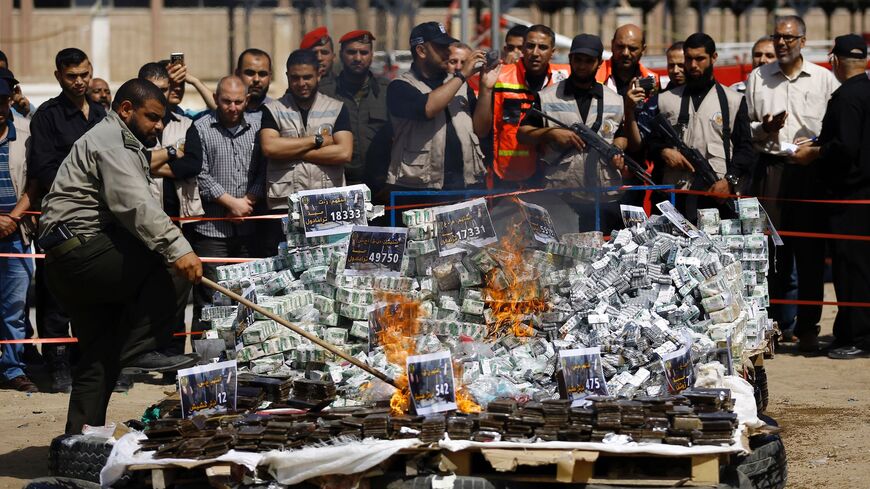 A member of the Hamas security forces sets fire to a pile of confiscated bars of hashish and analgesic pills.