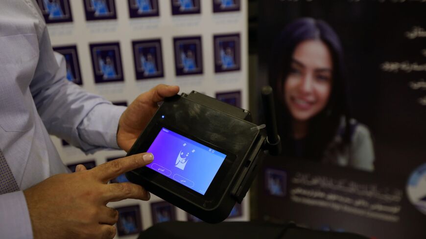 A member of Iraq's Electoral Commission demonstrates a digital machine that scans ballots of Iraqi voters.