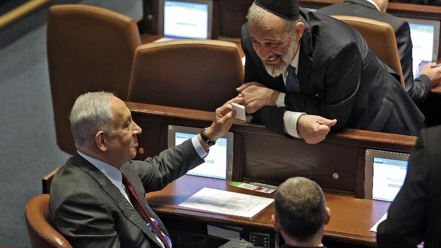 Israeli prime minister-designate Benjamin Netanyahu (L) speaks with key ally Aryeh Deri of the ultra-Orthodox Jewish party Shas, as they prepare to fast-track a change to the law to allow Deri to serve in cabinet despite past tax evasion convictions