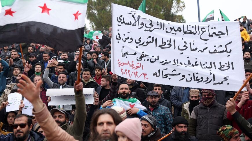 Demonstrators raise Syrian opposition flags and placards as they rally against a potential rapprochement between Turkey and the Syrian regime
