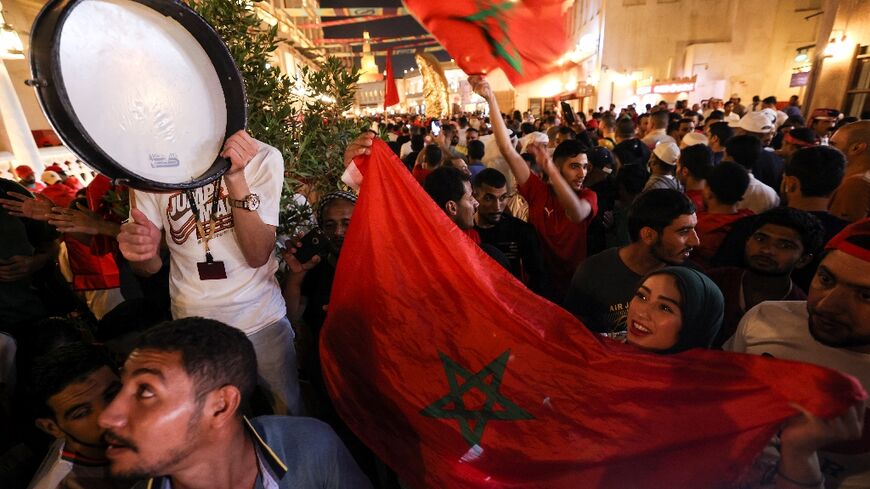 Morocco supporters in Doha's Souq Waqif celebrate their team's qualification for the last 16 of the World Cup