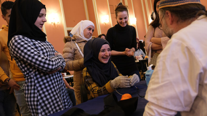 A young woman from Syria (seated) reacts to a mild electric current in the gloves she is wearing that is meant to simulate the effect of Parkinson's disease at a jobs fair for refugees that promotes training programs and jobs in the caregiving and health care industries on January 14, 2019 in Berlin, Germany. (Photo by Sean Gallup/Getty Images)