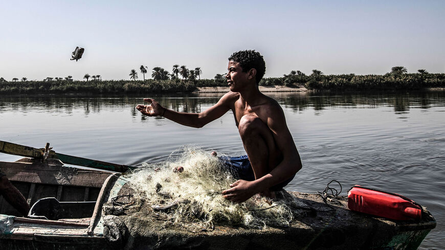 A fisherman tries to catch a freshly caught tilapia fish in a boat on the Nile River in the village of Gabal al-Tayr, north of the southern city of Minya, Egypt, Nov. 13, 2019.