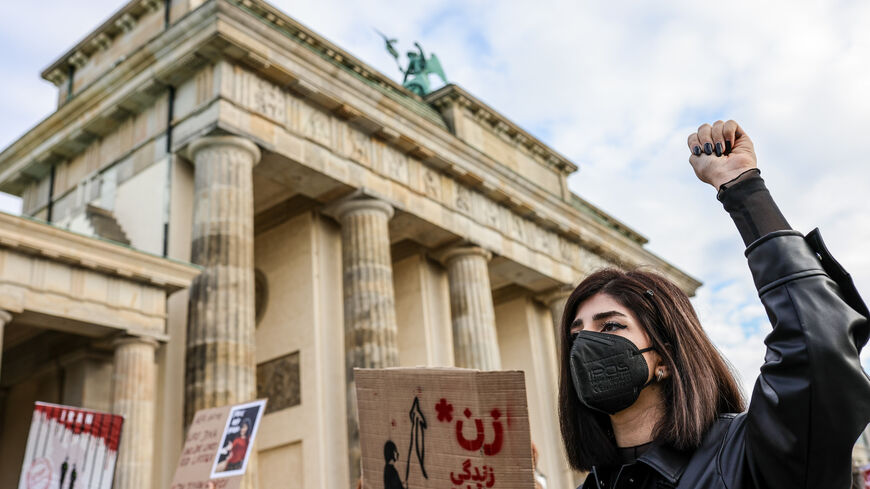 A protester wearing a face mask holds her fist in the air as demonstrators gather in front of the Brandenburg Gate to march in solidarity with protesters in Iran on October 15, 2022 in Berlin, Germany. (Photo by Omer Messinger/Getty Images)