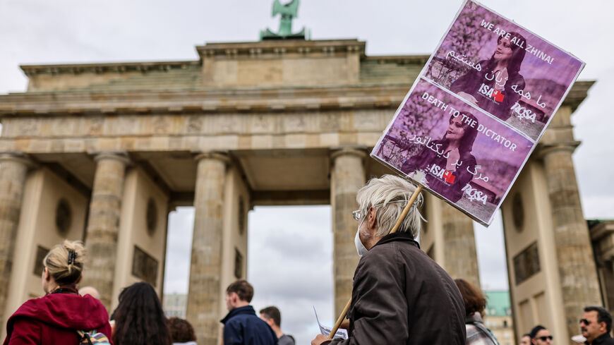 A protester holds a banner with the image of Mahsa Amini as demonstrators gather in front of the Brandenburg Gate to march in solidarity with protesters in Iran on October 15, 2022 in Berlin, Germany. (Photo by Omer Messinger/Getty Images)