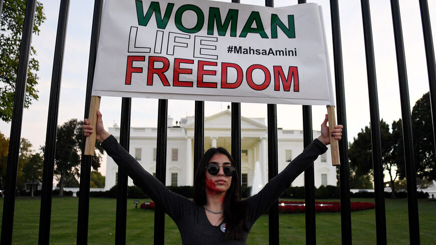 A woman holds a placard as protesters march in solidarity with protesters in Iran in front of the White House in Washington, DC, on October 22, 2022. - Iran has been rocked by protests since 22-year-old Mahsa Amini's death on September 16, three days after she was arrested by morality police in Tehran for allegedly violating the Islamic republic's strict dress code for women. (Photo by OLIVIER DOULIERY / AFP) (Photo by OLIVIER DOULIERY/AFP via Getty Images)