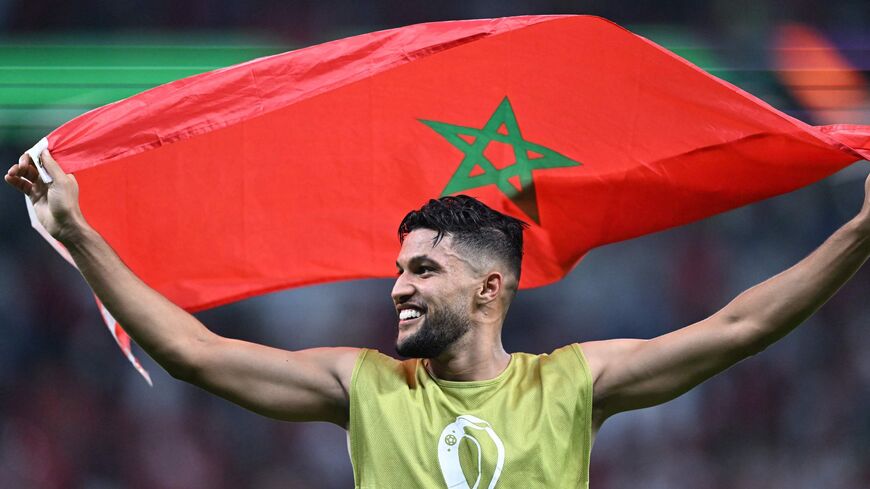 Morocco's defender #25 Yahya Attiyallah waves his national flag as he celebrates with supporters winning on penalty shoot-out the Qatar 2022 World Cup round of 16 football match between Morocco and Spain at the Education City Stadium in Al-Rayyan, west of Doha on December 6, 2022. (Photo by Kirill KUDRYAVTSEV / AFP) (Photo by KIRILL KUDRYAVTSEV/AFP via Getty Images)