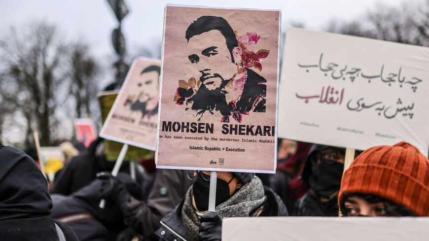 A participant holds a banner bearing an image of recently executed Iranian protester Mohsen Shekari.