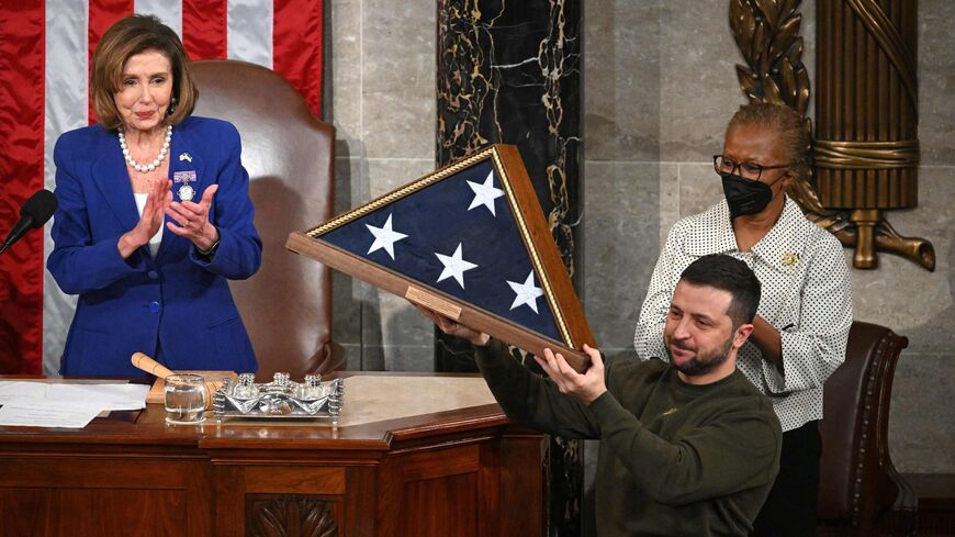 Ukraine's President Volodymyr Zelenskyy receives from US House Speaker Nancy Pelosi (D-CA) (L) a US national flag.