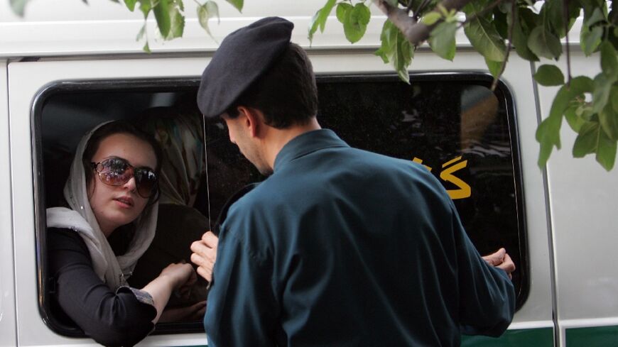 An Iranian officer (R) speaks with a woman arrested for wearing 'inappropriate' clothes in Tehran, on 23 July 2007