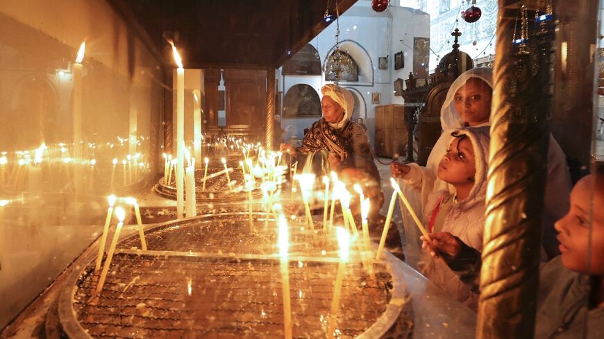 Pilgrims and tourists light candles inside the Church of the Nativity in the West Bank city of Bethlehem