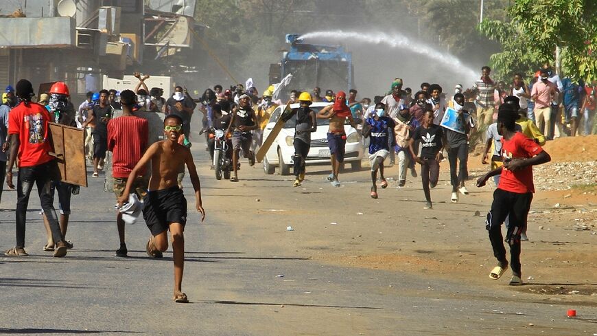 Demonstrators flee from a water cannon during clashes with security forces in Sudan's capital Khartoum on Monday, in rejection of a deal aimed at ending the crisis caused by the 2021 coup