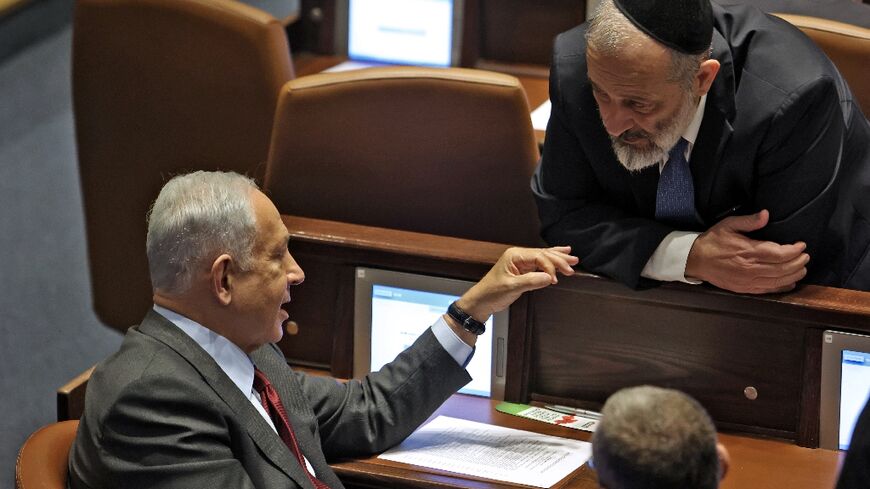 Israeli prime minister-designate Benjamin Netanyahu speaks with parliament member Aryeh Deri of the ultra orthodox  religious party Shas on December 13, 2022