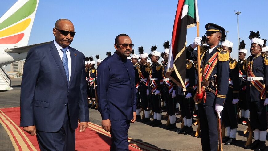 Ethiopian Prime Minister Abiy Ahmed (R) walks alongside Sudanese army chief Abdel Fattah al-Burhan (L) at Khartoum Airport during a welcome ceremony on January 26