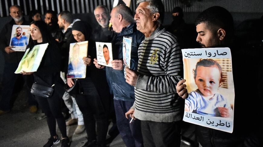 Relatives carry pictures of victims of the 2020 Beirut port blast as they protest in front of the residence of prosecutor general Ghassan Oueidat in Baabda, east of the capital Beirut