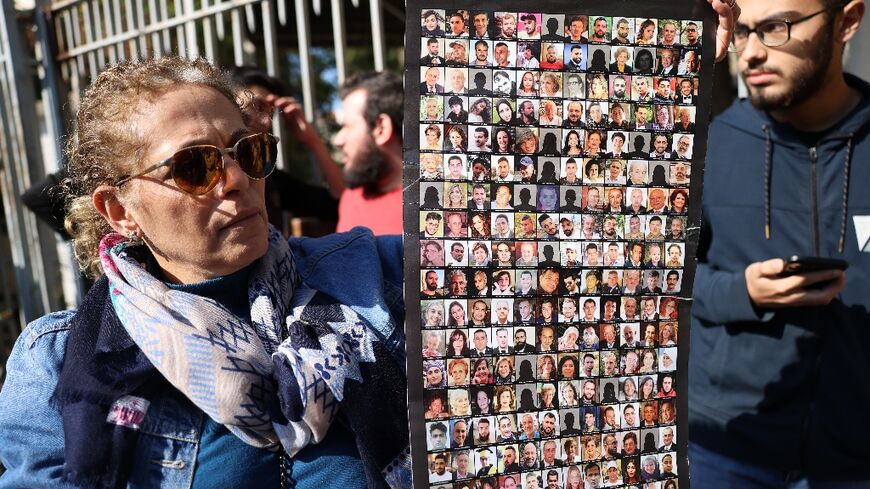 Relatives of victims of the 2020 Beirut port explosion, hold a poster bearing images of those killed in the blast as they rally outside the palace of justice in the Lebanese capital on Thursday