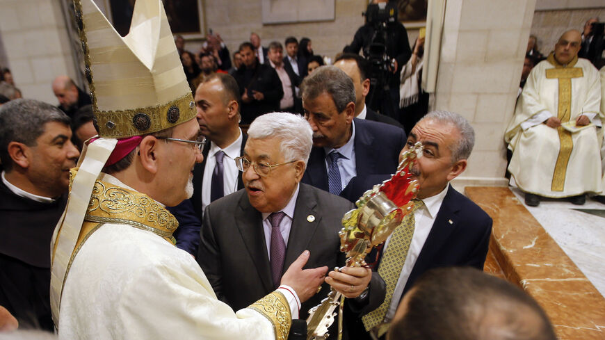 Palestinian President Mahmoud Abbas holds a wooden relic reputed to be part of Jesus's manger, as he speaks with the acting Latin Patriarch of Jerusalem Pierbattista Pizzaballa during a Christmas midnight mass in the Church of the Nativity, in Bethlehem in the Israeli-occupied West Bank December 25, 2019. (Photo by MUSSA QAWASMA/POOL/AFP via Getty Images)