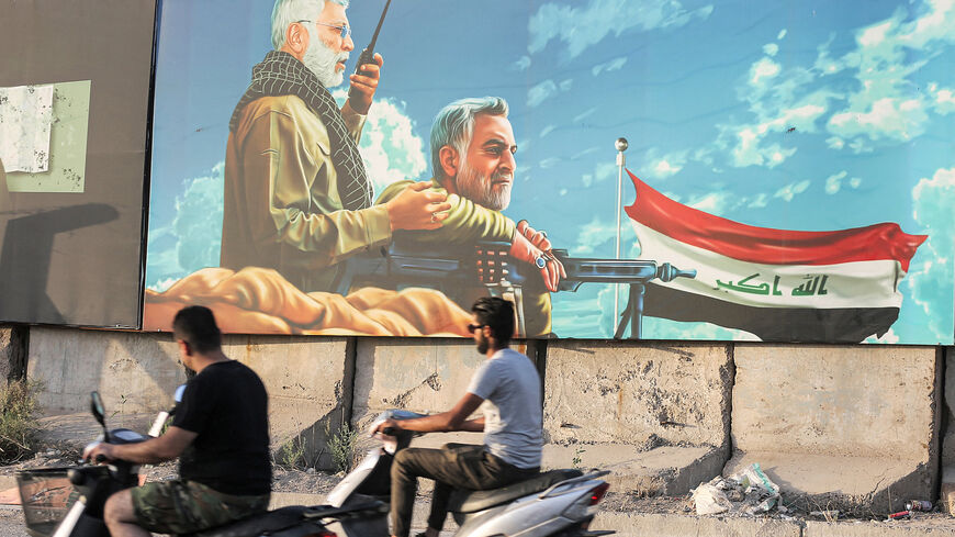 Men ride scooters past a billboard depicting (L to R) the late commander of the Popular Mobilization Units Abu Mahdi al-Muhandis and Iran's Islamic Revolutionary Guard Corps commander Qassem Soleimani, Baghdad, Iraq, June 13, 2021.