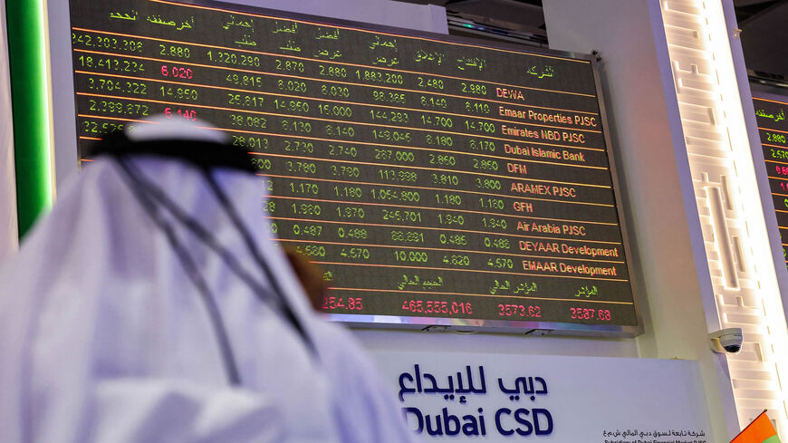 A man watches stock movements on a display at the Dubai Financial Market stock exchange, Dubai, United Arab Emirates, April 12, 2022.