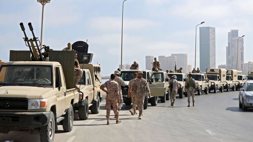 Vehicles of forces loyal to Libya's Tripoli-based Prime Minister Abdulhamid Dbeibah are parked along the waterfront (with the "That El Emad Towers" complex seen in the background) in the capital Tripoli on May 17, 2022 hours after forces of the rival Tobruk-based government withdrew following heavy fighting between opposing militias.  (Photo by MAHMUD TURKIA/AFP via Getty Images)