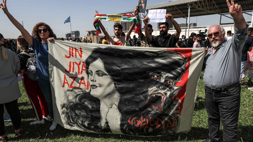 A man and a woman hold up a banner depicting the image of 22-year-old Mahsa Amini, who died while in the custody of Iranian authorities, during a demonstration denouncing her death by Iraqi and Iranian Kurds outside the UN offices in Arbil, the capital of Iraq's autonomous Kurdistan region, on September 24, 2022. (Photo by SAFIN HAMED/AFP via Getty Images)