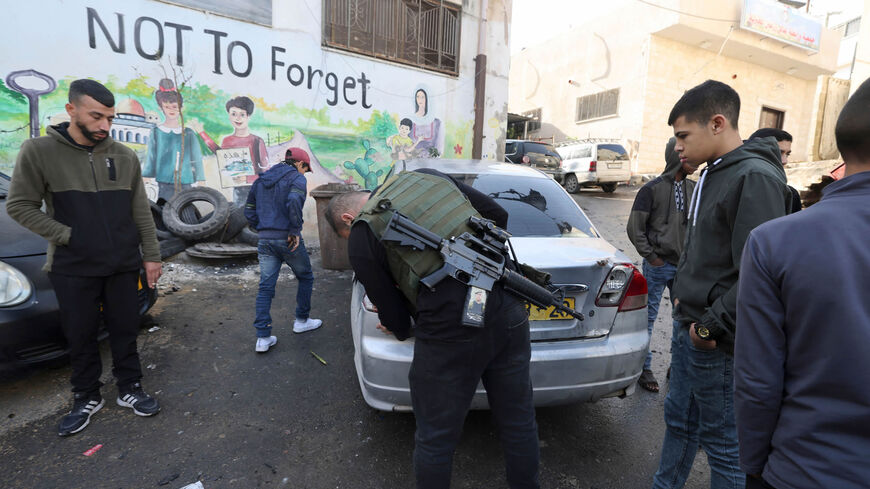 Palestinian residents and gunmen inspect the damage following the accidental explosion of an improvised explosive device in Jenin refugee camp, near the city of Jenin, West Bank, Dec. 12, 2022.