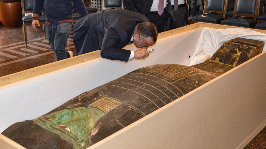 Mostafa Waziri, the head of Egypt's Supreme Council of Antiquities, uses a magnifying glass to inspect an ancient Egyptian wooden sarcophagus being handed over and which was formerly displayed at Houston Museum of Natural Sciences after having been looted and smuggled years prior, at the foreign ministry headquarters in the capital Cairo on January 2, 2023. Photo by -/AFP via Getty Images)