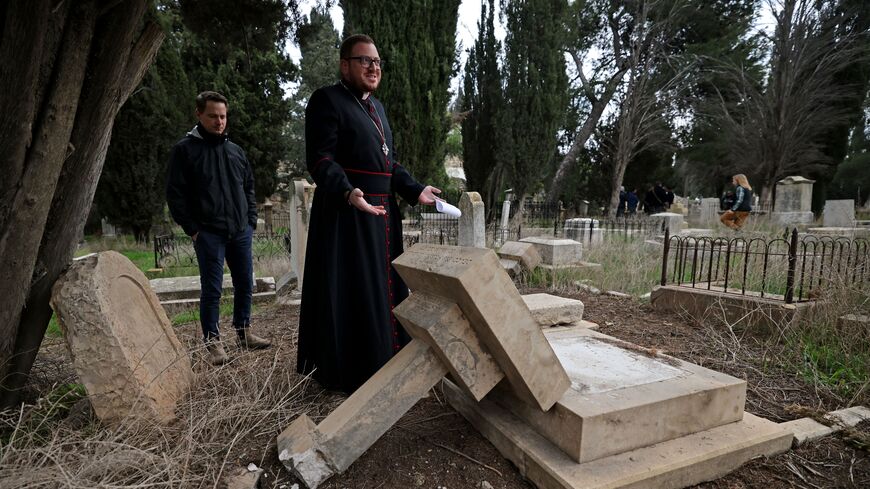 Caretakers of the Protestant cemetery inspect vandalised graves on Mount Zion outside Jerusalem's Old City on January 4, 2023. - (Photo by AHMAD GHARABLI/AFP via Getty Images)