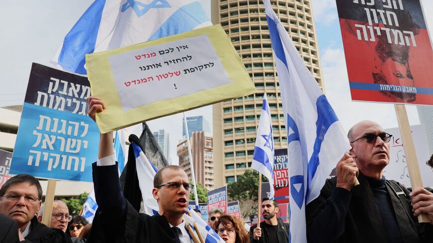 A man holds a sign with writing in Hebrew reading "we won't let you go back to the old days of the British Mandate" during a demonstration by lawyers against the Israeli government's controversial plans to overhaul the judicial system, outside the Tel Aviv District Court of Justice on January 12, 2023.  (Photo by JACK GUEZ/AFP via Getty Images)