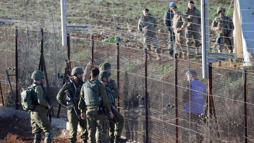 A picture taken from the northern Israeli town of Metula near the border with Lebanon shows a member of the United Nations Interim Force in Lebanon talking with Israeli soldiers through the border fence, on the outskirts of the southern village of Kfarkila, Lebanon, Jan. 19, 2023.