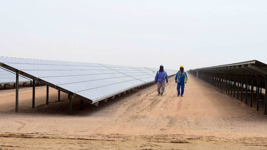 Employees walk past solar panels at the Mohammed bin Rashid Al-Maktoum Solar Park, Dubai, March 20, 2017.