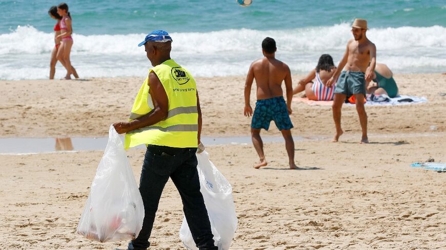 A cleaner collects plastic garbage at a Tel Aviv beach