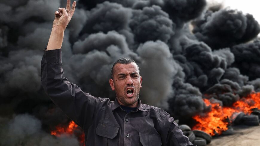 A Palestinian man gestures near burning tyres during a protest east of Jabalia refugee camp