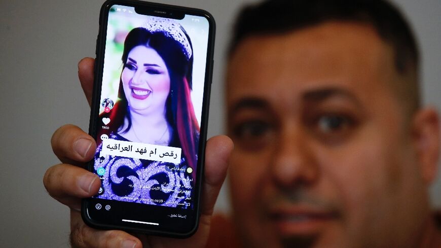 An Iraqi man holds a phone showing a picture of TikTok celebrity Om Fahed