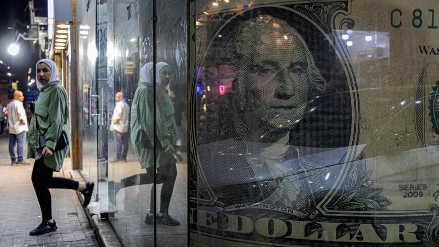 A woman walks out of a currency exchange shop displaying a giant US dollar banknote.