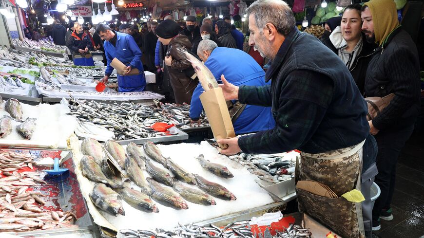 A fisherman sells his fish at a public market where customers shop  in the historical district of Ulus in Ankara on December 30, 2022. (Photo by ADEM ALTAN/AFP via Getty Images)