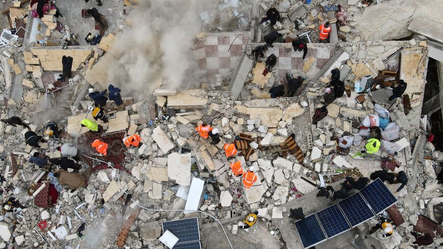 This aerial view shows residents helped by bulldozers, searching for victims and survivors in the rubble of collapsed buildings, following an earthquake in the town of Sarmada in the countryside of the northwestern Syrian Idlib province, early on February 6, 2023. Over 1,500 people have been killed in the earthquake that hit Turkey and Syria. (Photo by MUHAMMAD HAJ KADOUR/AFP via Getty Images)