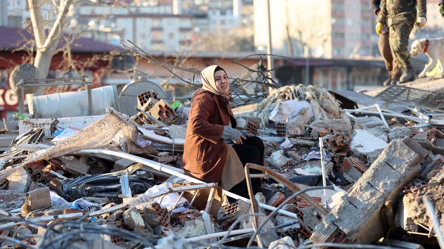 A woman sits on the rubble of a destroyed building in Kahramanmaras, southern Turkey, a day after a 7.8-magnitude earthquake struck the country's southeast, on Feb. 7, 2023.  
