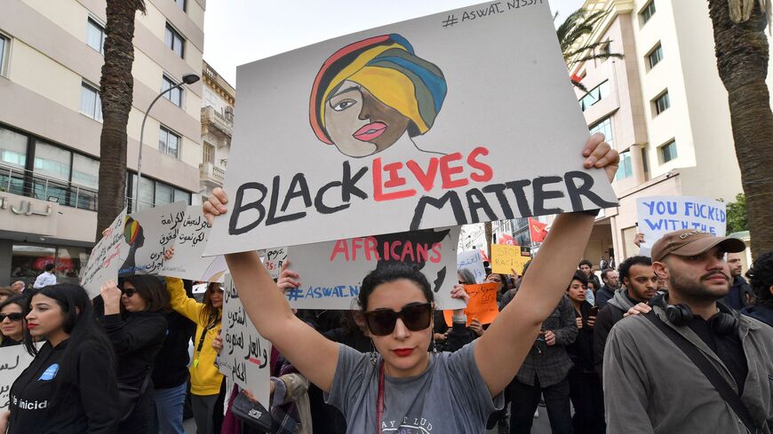 Protesters lift placards during a demonstration in Tunis on Feb. 25, 2023.