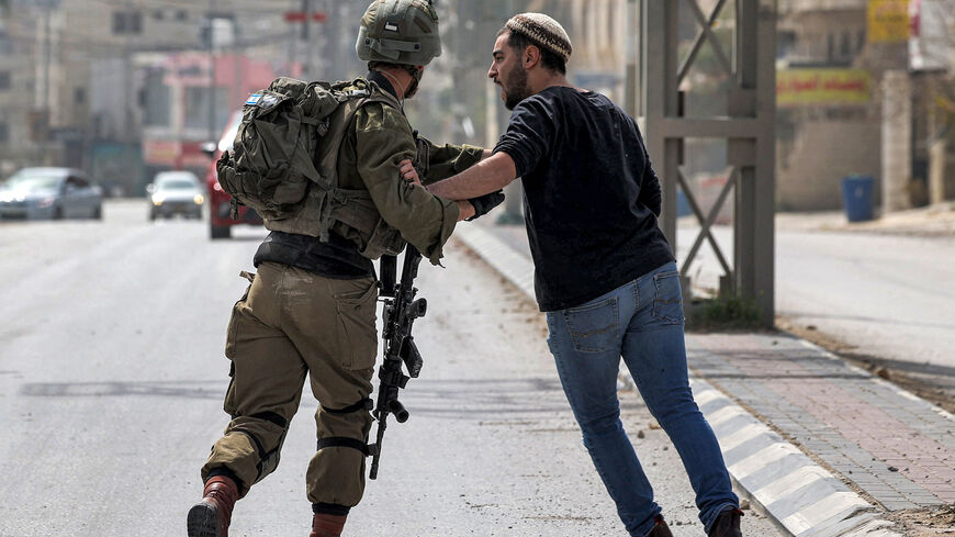 An Israeli settler (R) argues with an Israeli soldier along a road in the town of Huwara.