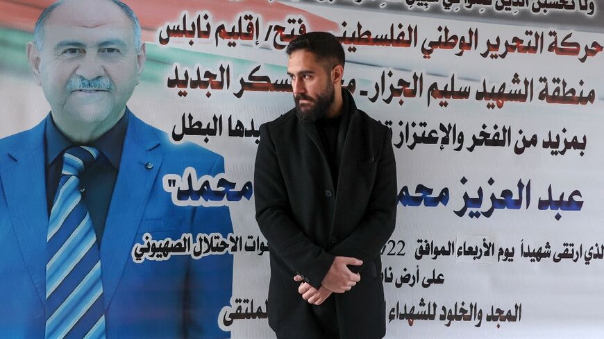 Palestinian nurse Elias al-Ashqar poses in front of a death notice for his father Abdel Aziz, whom he spotted in the Nablus hospital where he works among the dead from this week's Israeli raid on the city