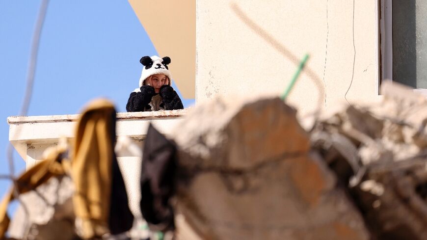 A young resident of a still standing building watches continuing search operations in the Syrian government-controlled town of Jableh