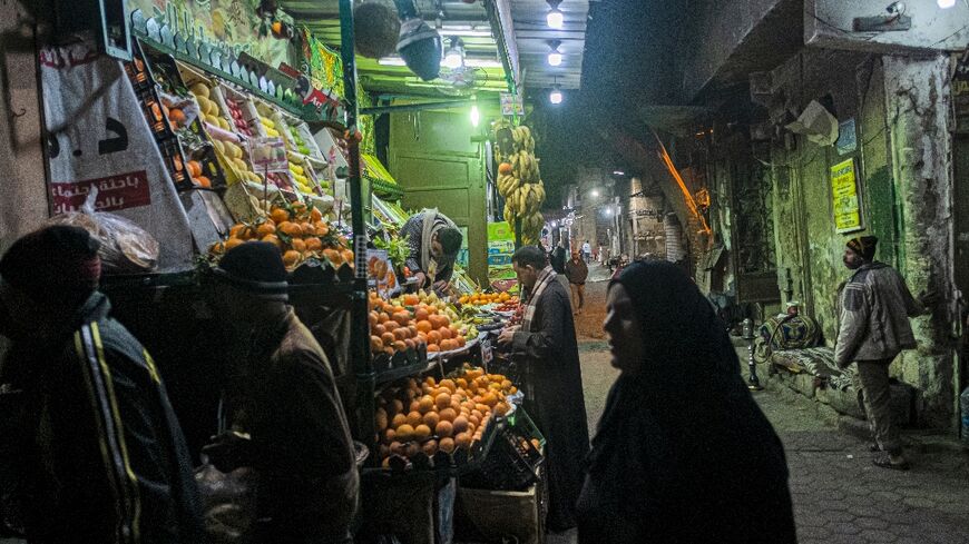 People walk past a fruit seller's stall in the Azhar district of Egypt's capital Cairo on January 16: many ordinary Egyptians are struggling amid an economic crisis